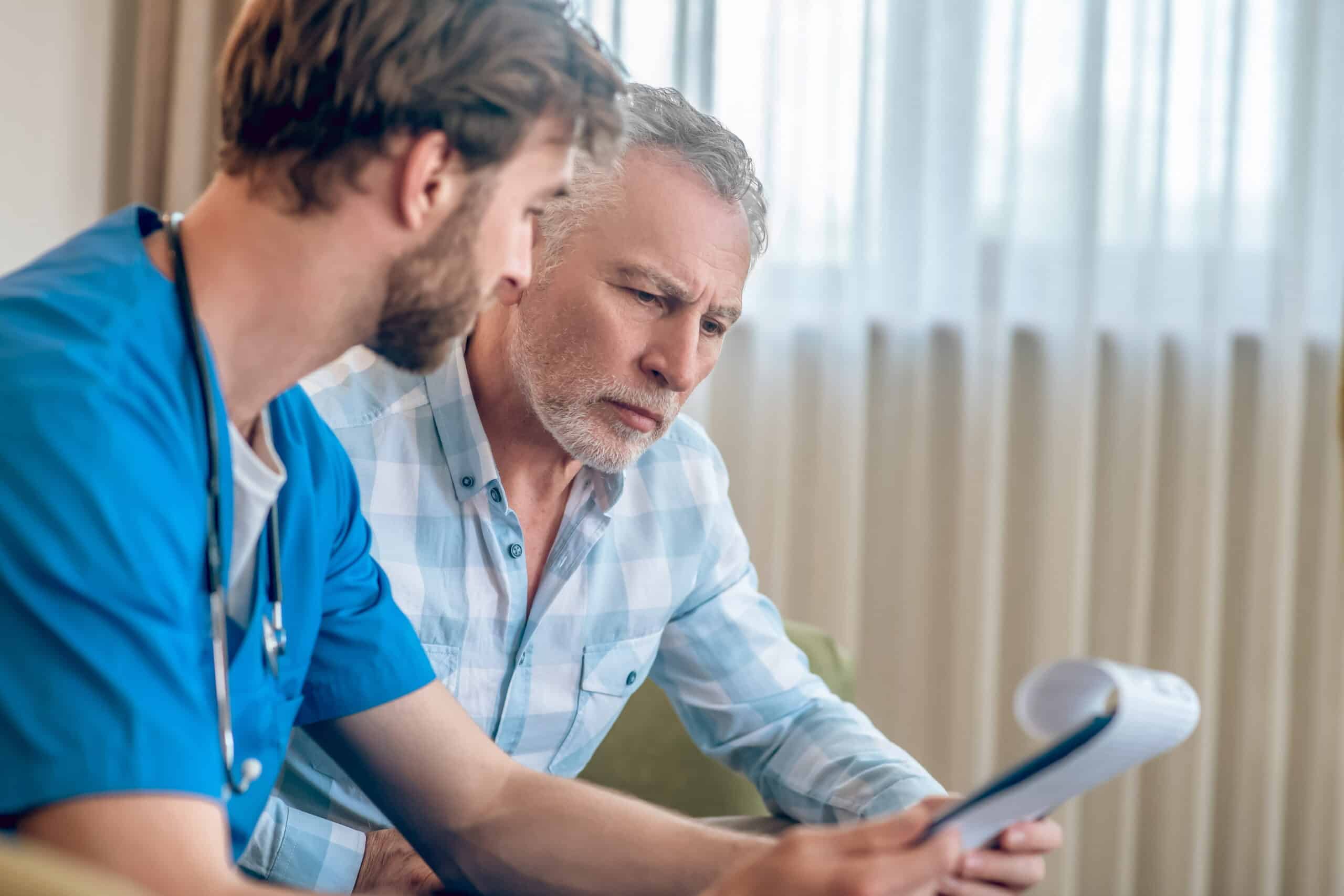 A healthcare professional reviewing documentation with an older client during an in-home assessment